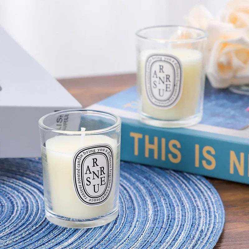 Two small, ivory-coloured scented candles in clear glass votives with oval, minimalist typography labels.