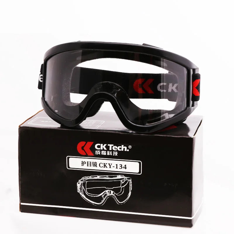 Black safety goggles with clear lenses and an adjustable strap rest on a matching black product box.