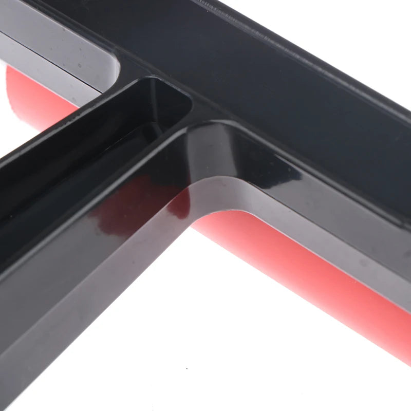 Close-up of a black plastic T-shaped handle attached to a smooth, red cylindrical rubber roller.