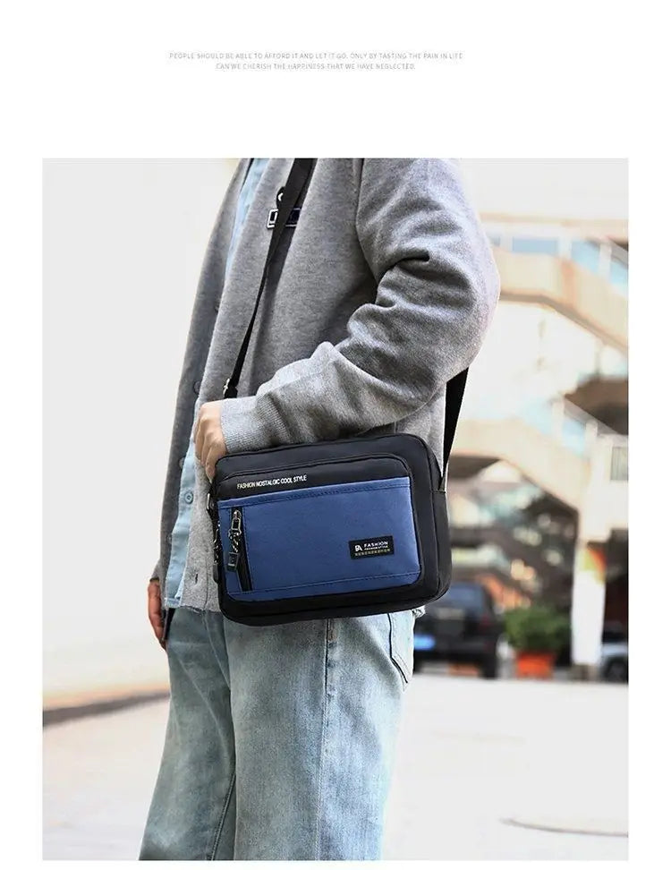 A man wearing a black and blue rectangular crossbody bag with a front zip pocket and adjustable shoulder strap.