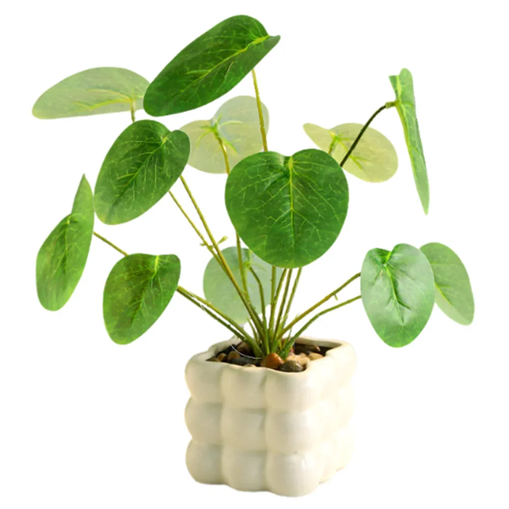Artificial green money plant in a textured, square white ceramic pot filled with small decorative pebbles.