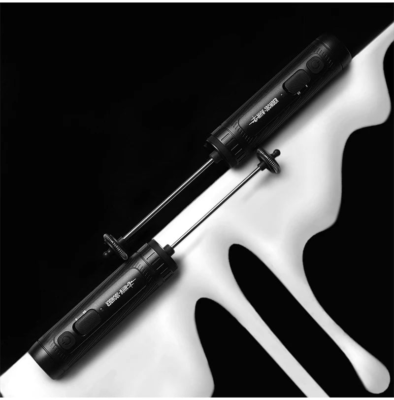 Two matte black, sleek, cylindrical handheld electric milk frothers against a stylized white and black background.