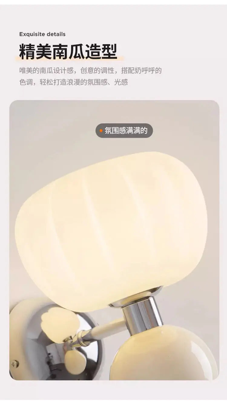 Cream-coloured, pumpkin-shaped wall lamp with a metallic silver base, emitting a warm, soft glow.