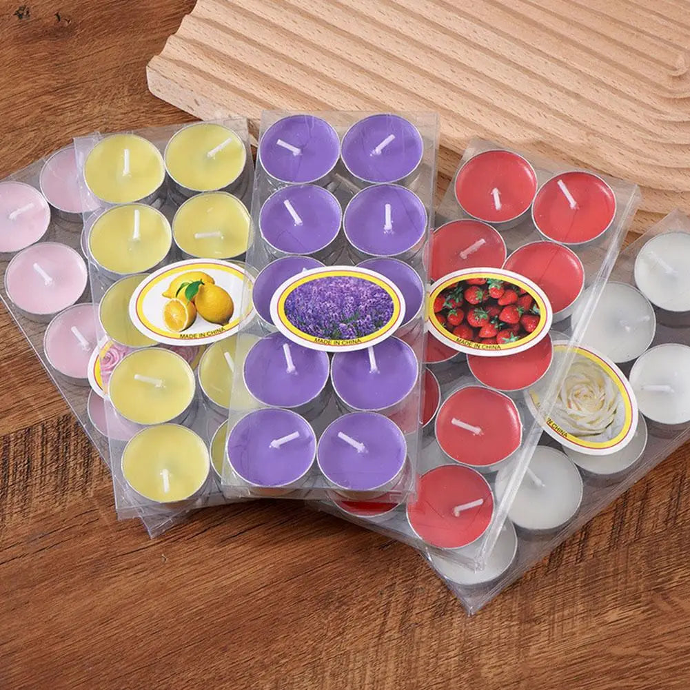 Four packs of scented tea light candles in yellow, purple, red, and white, displayed on a wooden surface.