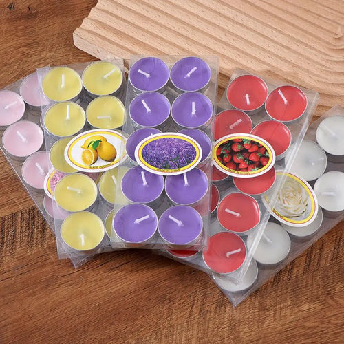Four packs of scented tea light candles in yellow, purple, red, and white, displayed on a wooden surface.