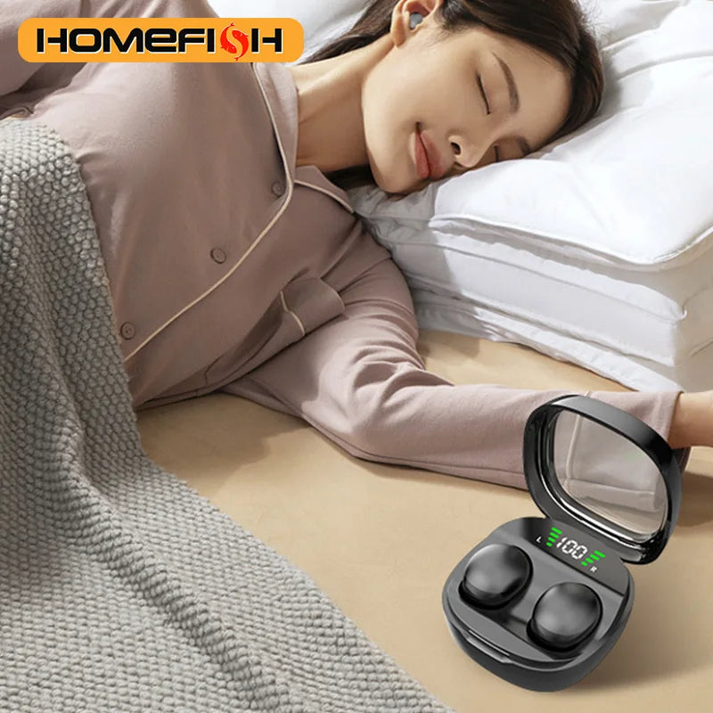 Black wireless earbuds in a charging case with a digital battery display, next to a person sleeping in bed.