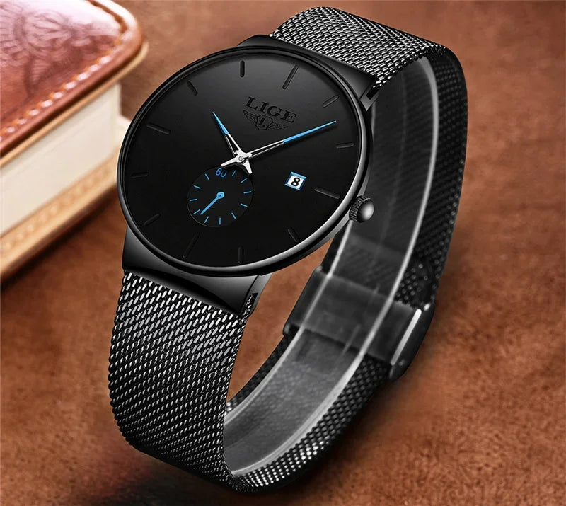Elegant ultra-thin black women's watch with a stainless steel mesh strap, black dial, and blue hands.