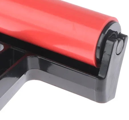 Close-up of a craft brayer with a vibrant red rubber roller and a durable black plastic handle.