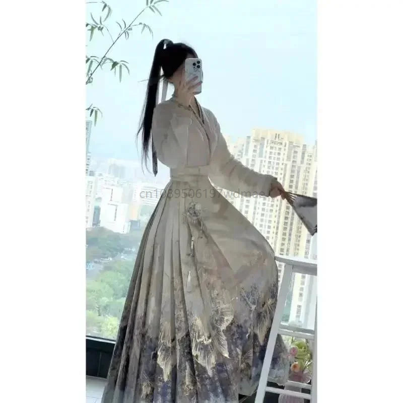 Woman in a beige, long-sleeved traditional-style dress with a pleated skirt featuring a blue and grey mountain print.