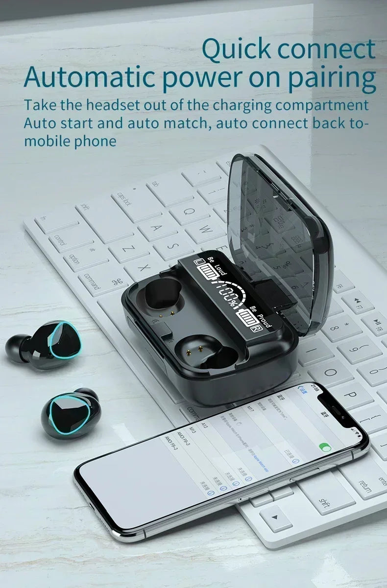 Black wireless earbuds with teal light rings and a matching digital display charging case on a white keyboard.