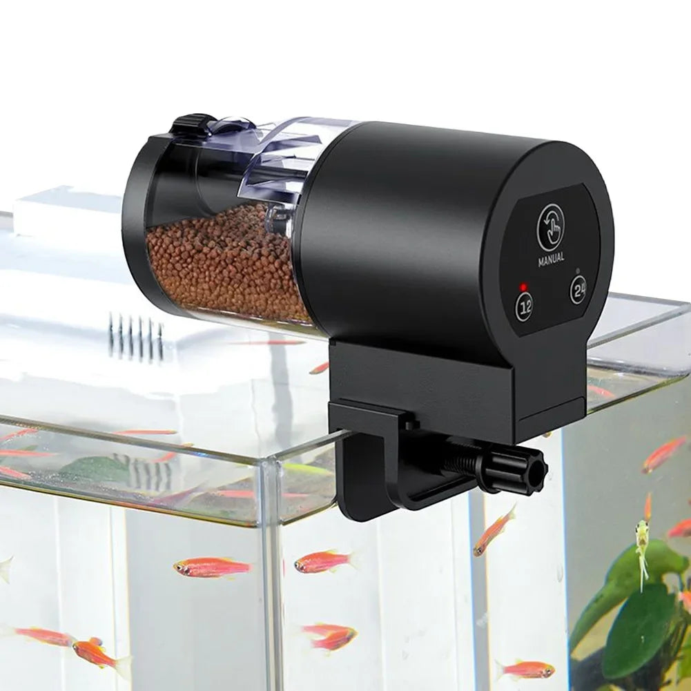 Black automatic fish tank feeder with a clear food canister, clamped to the edge of a glass aquarium.