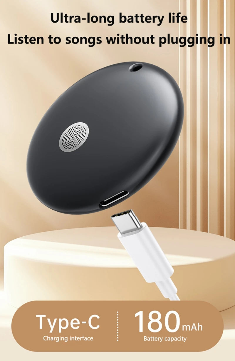 A sleek, matte black round portable shower speaker being charged with a white USB-C cable against a neutral background.