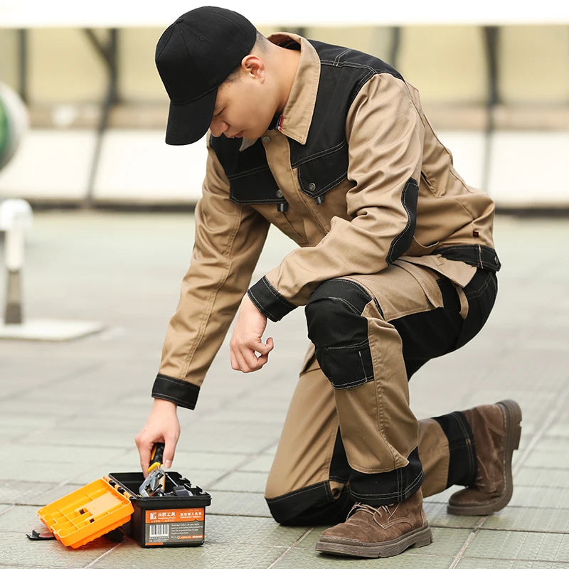 A man kneeling in two-tone khaki and black cotton cargo work trousers with reinforced knees and multiple pockets.