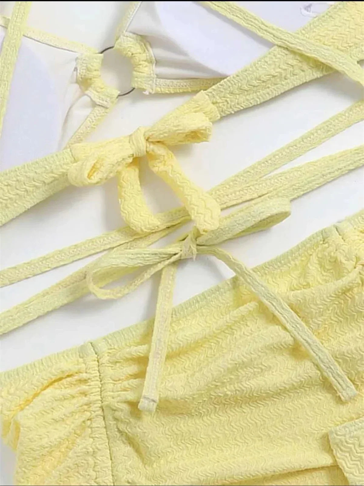Yellow textured bikini top with halter neck, ring link, criss-cross straps, and tie closures.