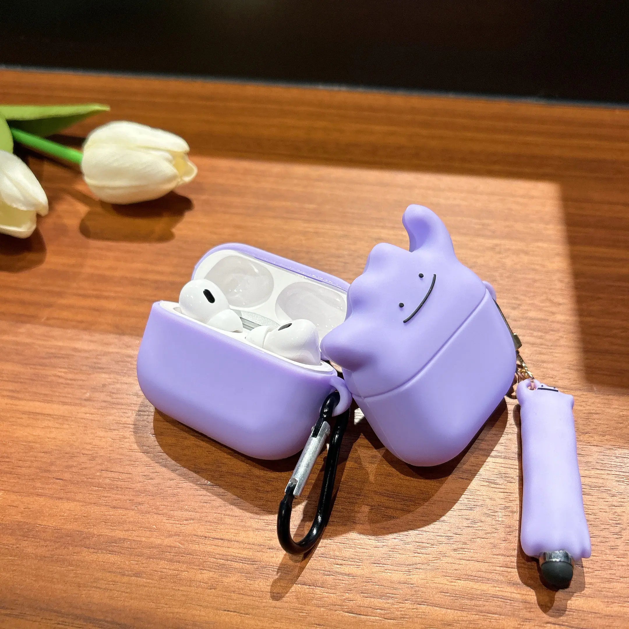Purple silicone AirPods Pro case shaped like Ditto, featuring a character charm and black carabiner.