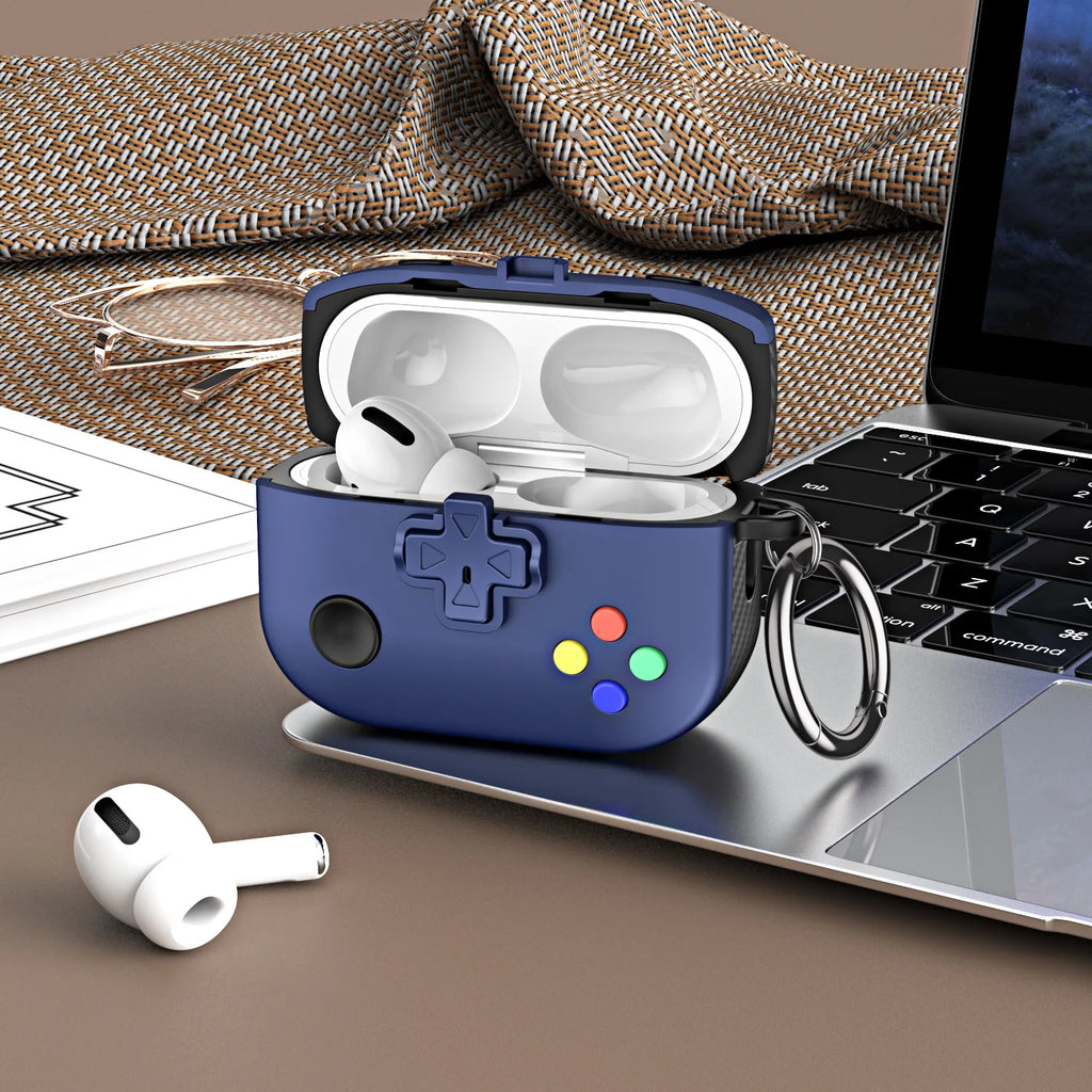 Navy blue silicone gaming controller-style case for AirPods Pro with a keychain hook, on a desk next to a laptop.
