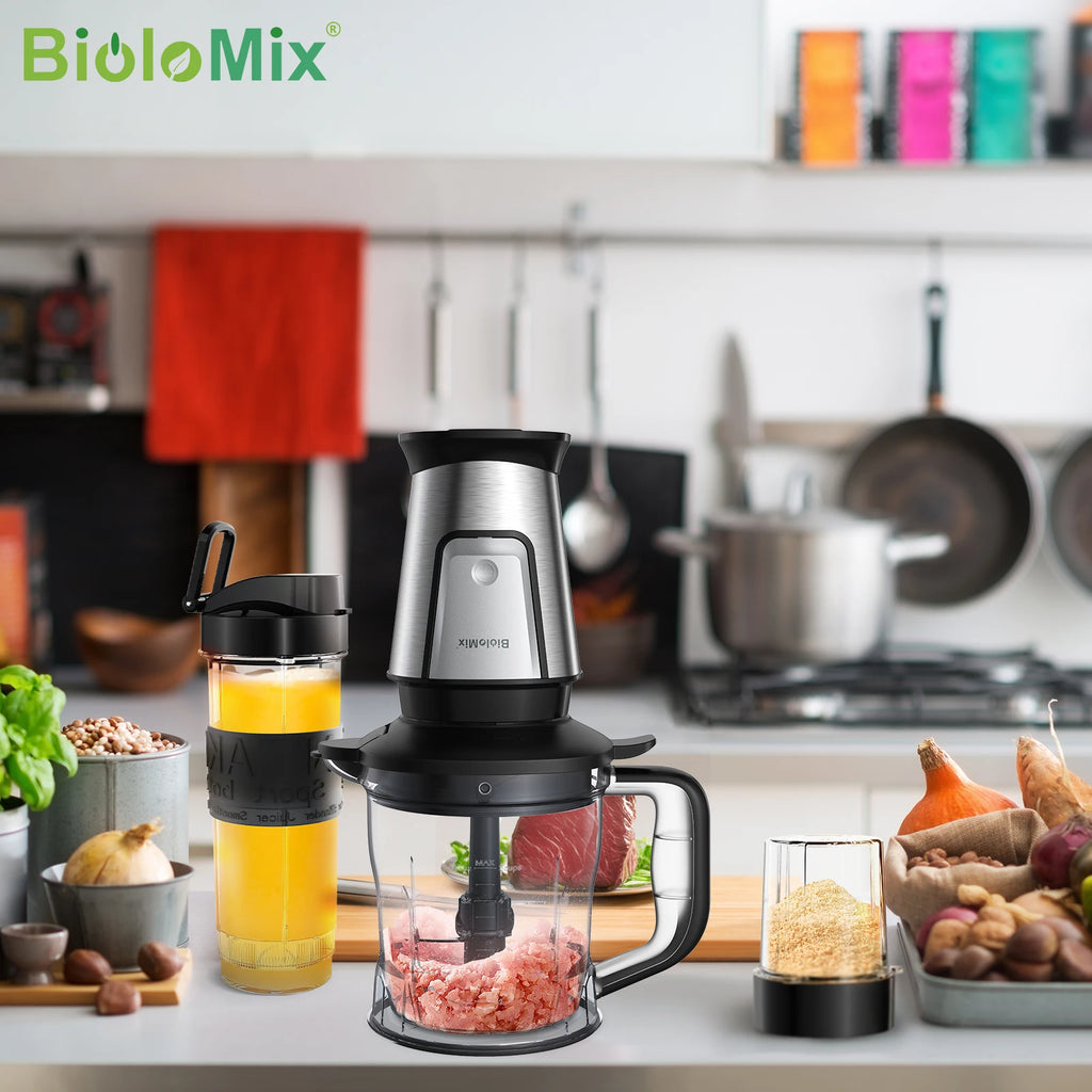 Stainless steel food processor with clear bowl and black accents, plus a portable blending cup on a kitchen counter.