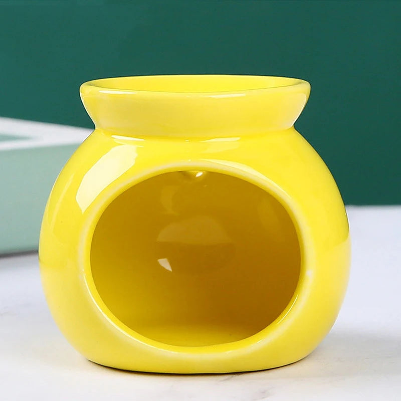 Glossy, round, bright yellow ceramic wax melt or oil burner with a wide front opening on a white surface.