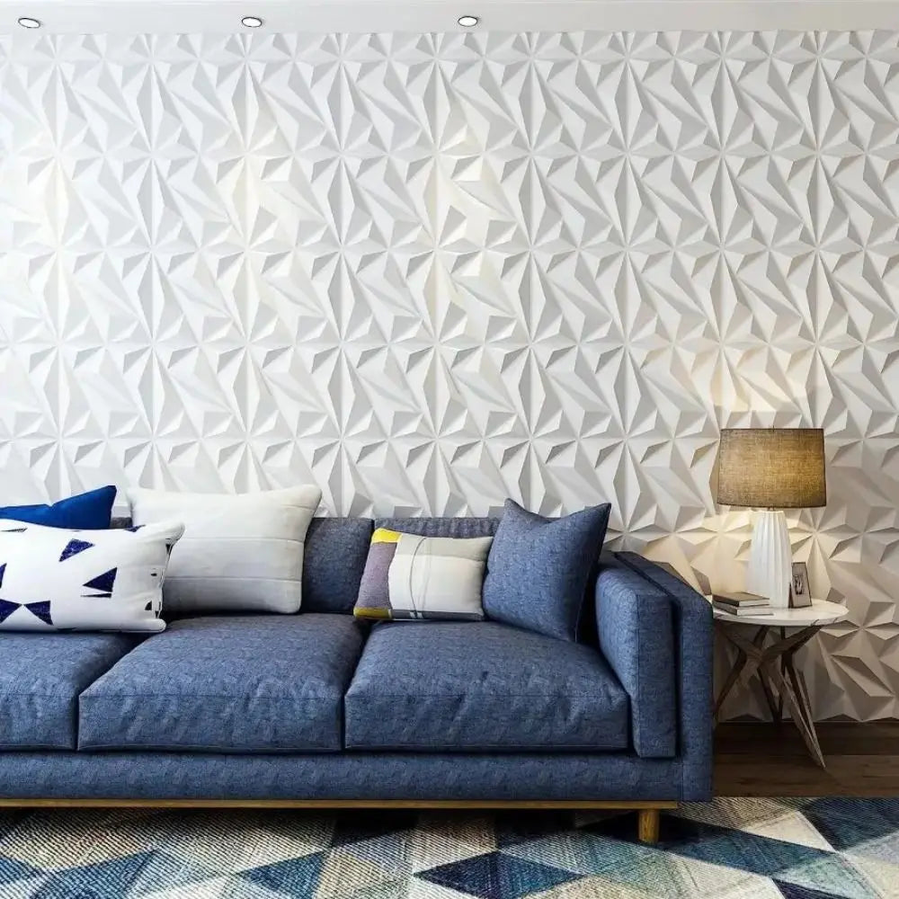 White 3D decorative wall panels with a geometric diamond pattern, styled behind a contemporary blue sofa.