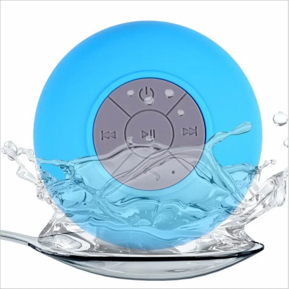 Blue waterproof Bluetooth speaker with a grey control panel and suction cup base, shown splashed with water.