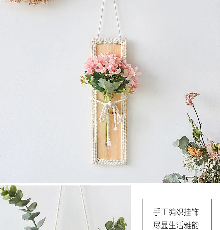 Bohemian wall hanging featuring a wooden plaque with rope border, tied with rope and decorated with pink silk flowers.