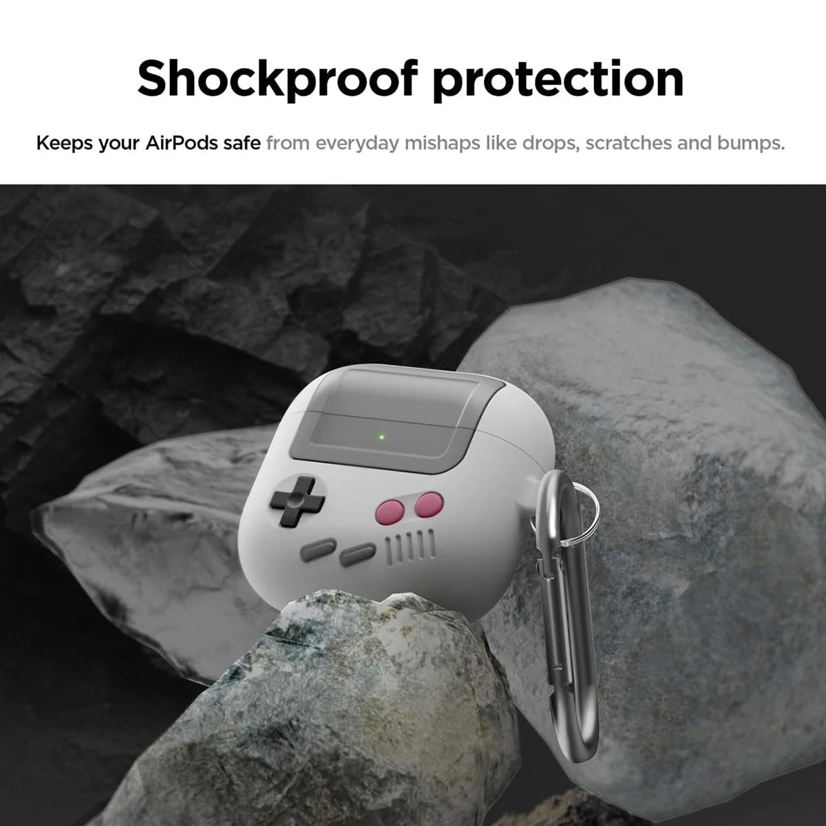 Grey and white retro console-style silicone AirPods case with a metal carabiner, resting on rocks.