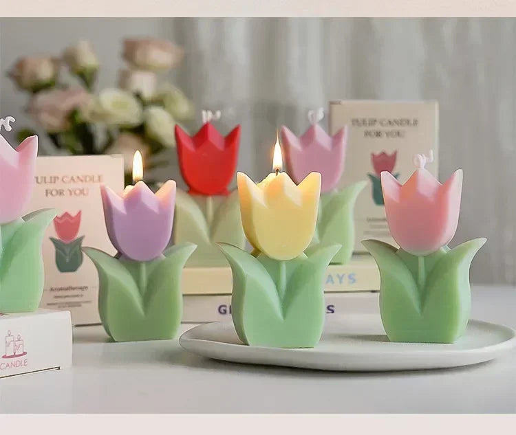 Assorted colourful tulip-shaped candles in pastel and bright wax, featuring green stems and leaves, on a white tray.