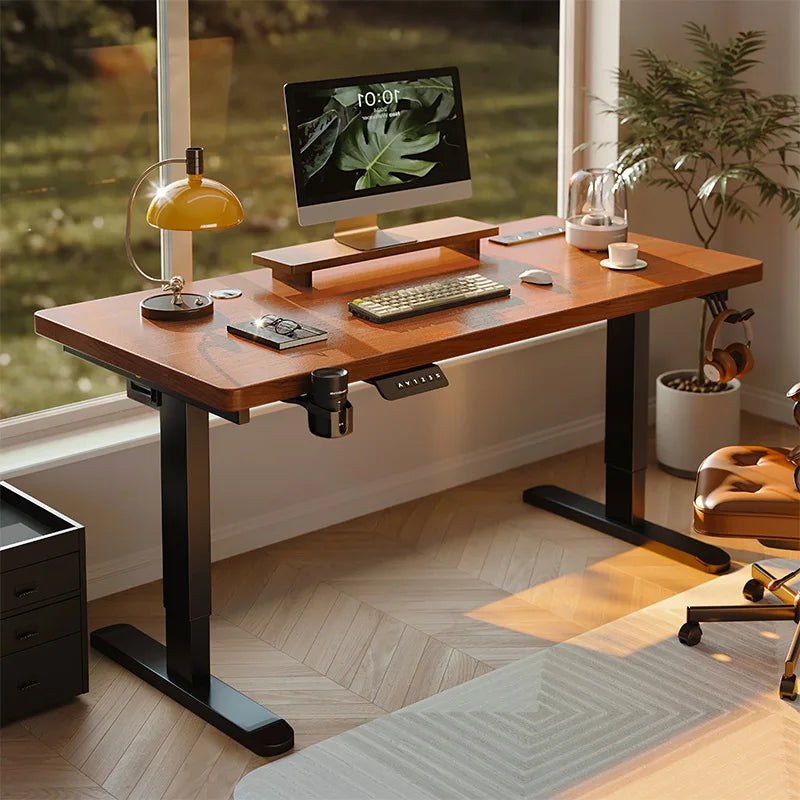 A wooden standing desk with black metal legs, a monitor, keyboard, and lamp in a well-lit home office.