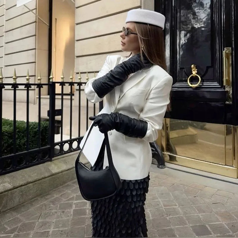 Elegant white wool pillbox-style hat worn by a woman in a smart white blazer and black accessories.