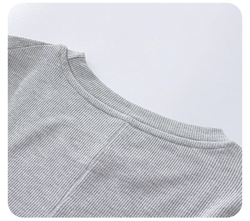 Close-up of a light grey ribbed knit top featuring a comfortable crew neckline and textured fabric detail.
