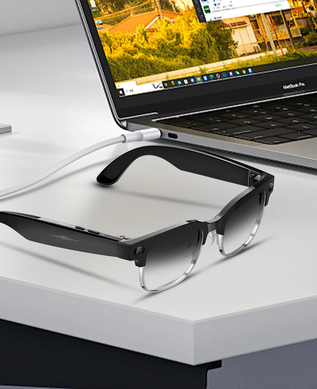 Black smart recording glasses with gradient lenses and integrated camera, sitting on a desk next to a laptop.