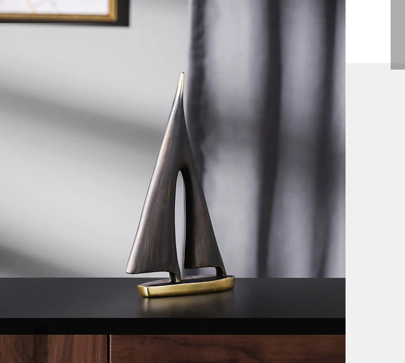 Modern abstract sailboat ornament in a dark bronze finish with a sleek gold-tone base.
