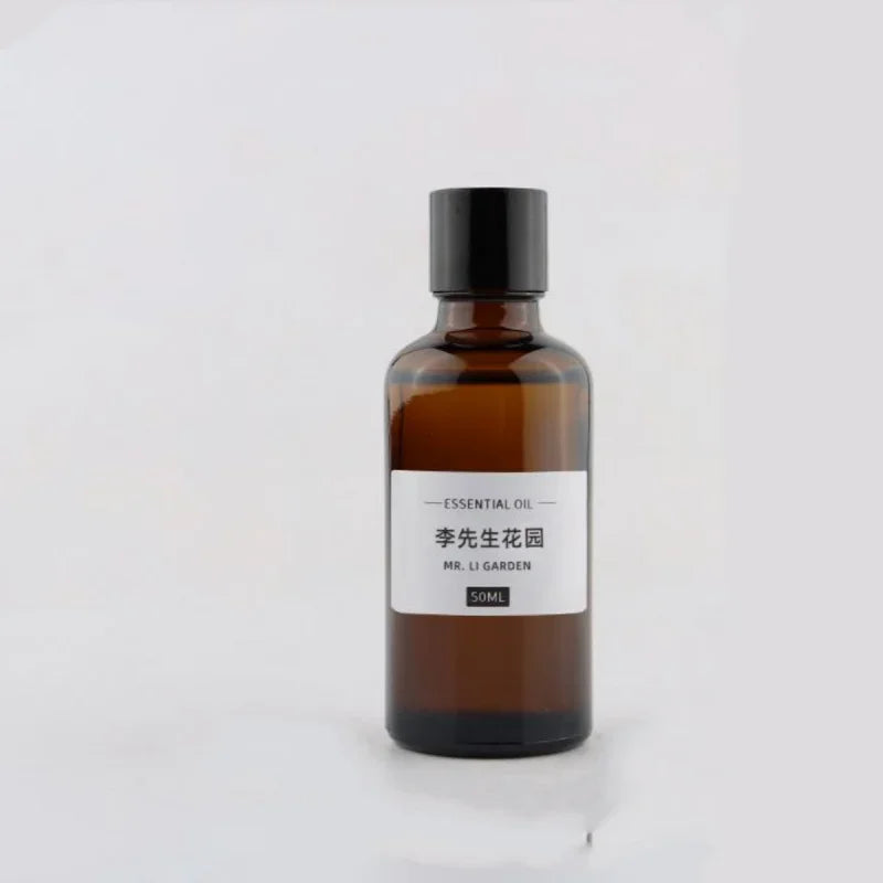Amber 50ml essential oil glass bottle with a black screw cap and minimalist white label, isolated on white background.