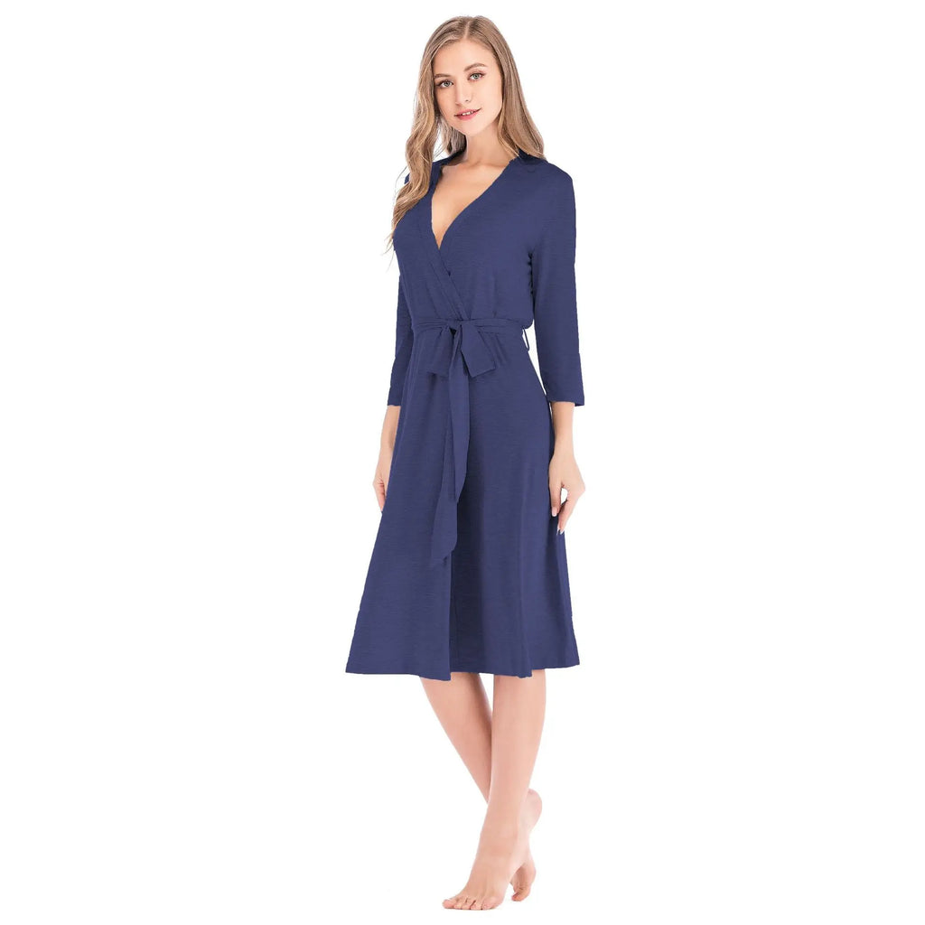 A woman wearing a navy blue knee-length wrap robe with three-quarter sleeves and a matching fabric waist tie.