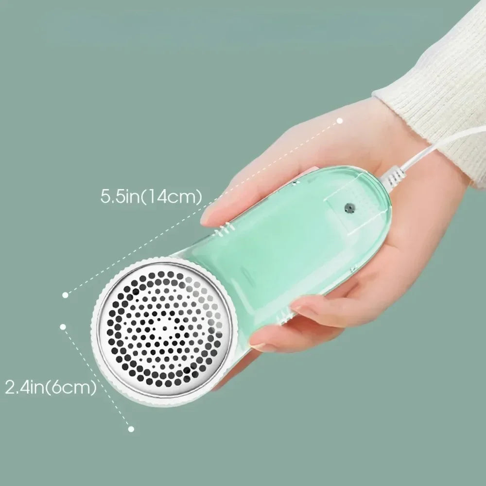 Hand holding a compact, mint green electric fabric shaver with a white mesh head, shown with size dimensions.
