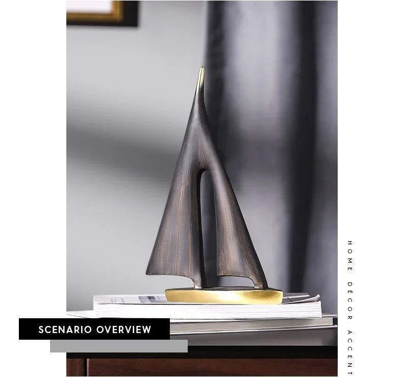 Abstract dark bronze sailboat ornament with a gold base, styled as minimalist nautical decor on top of books.