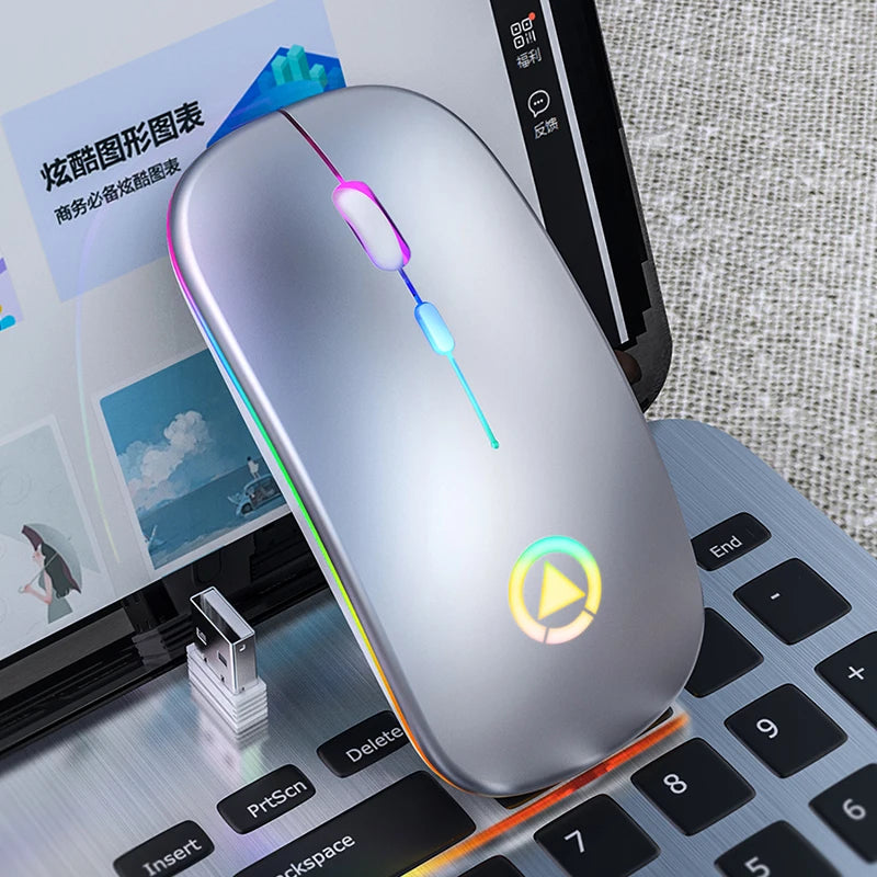 Silver ergonomic wireless mouse with colourful LED lighting, resting on a laptop keyboard with a USB receiver.