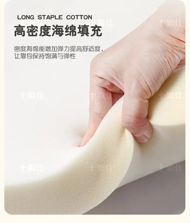 A hand pressing into a piece of soft, high-density white foam used for the bed's cushioned headboard padding.