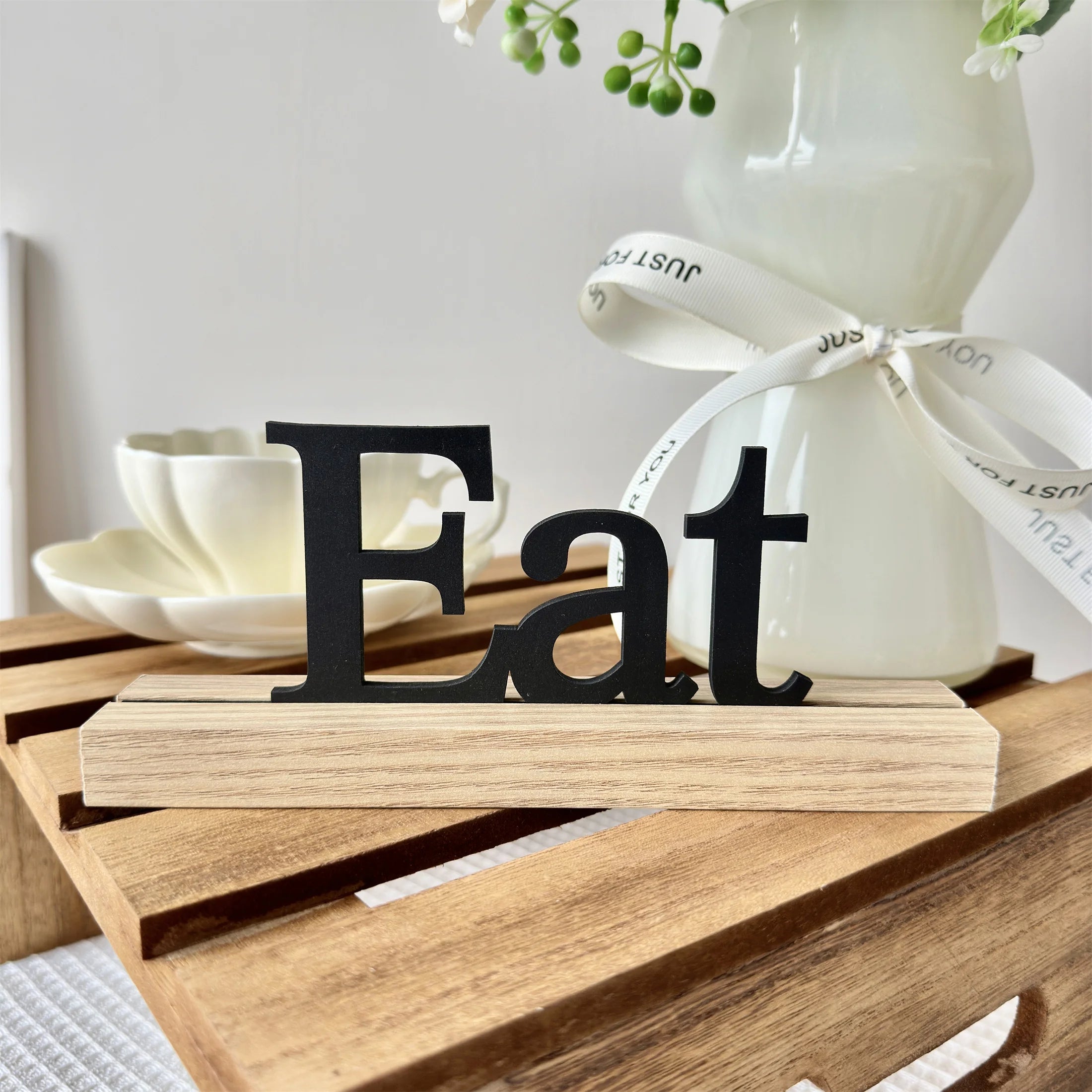 Black wooden "Eat" sign mounted on a natural light wood base, displayed on a rustic wooden crate.