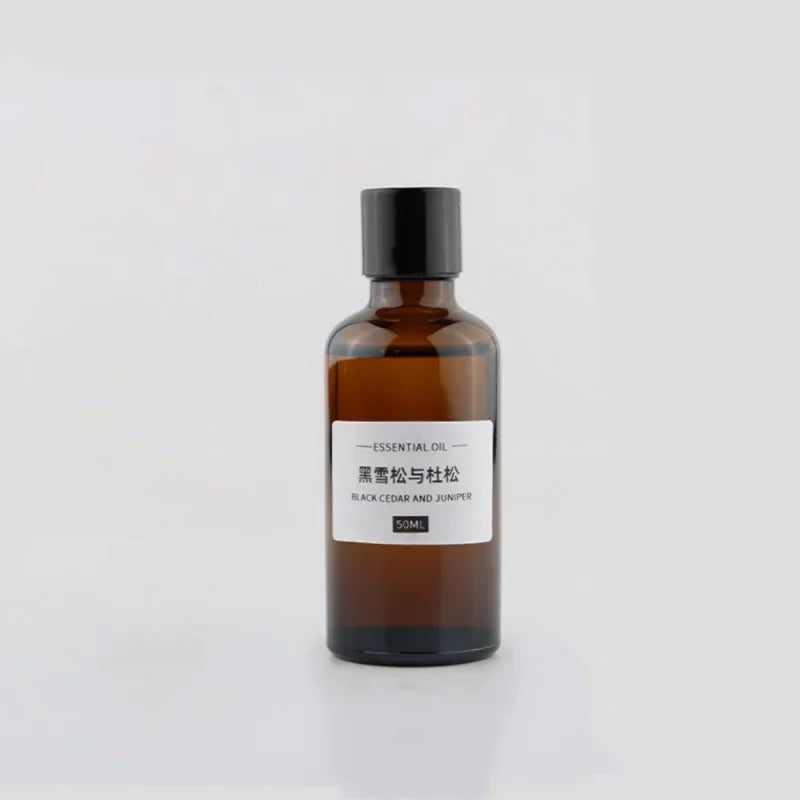 50ml amber glass bottle of Black Cedar and Juniper essential oil with a black screw cap and minimalist white label.