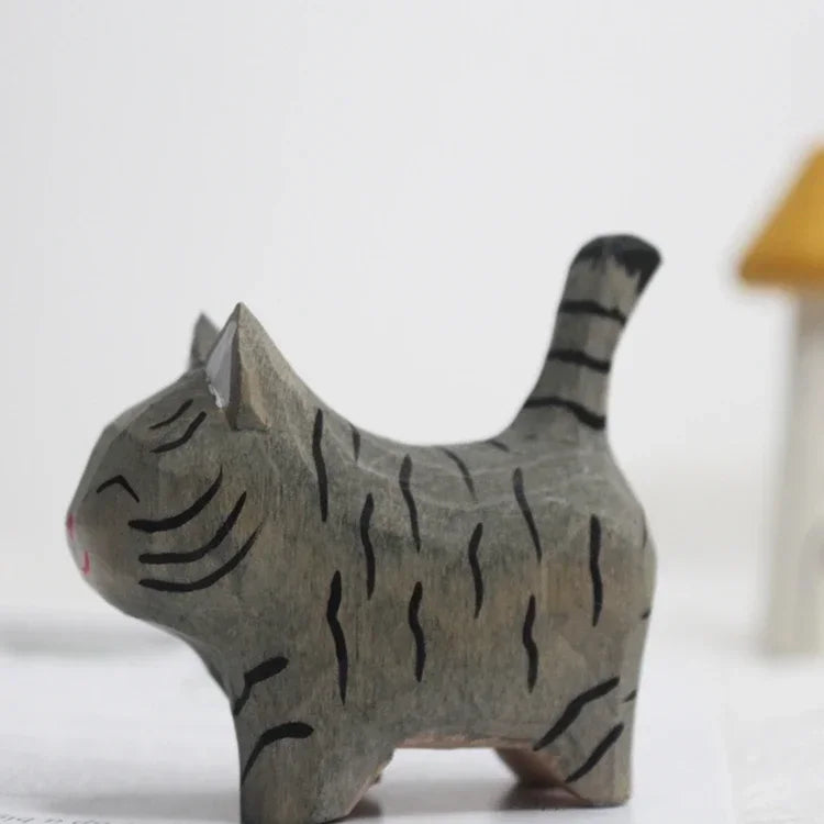 Small hand-carved wooden cat figurine in grey with painted black stripes and a happy, closed-eye expression.