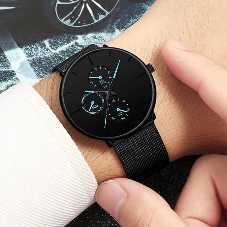 Ultra-thin men's watch with a black mesh stainless steel strap, black dial, and striking blue-accented sub-dials.