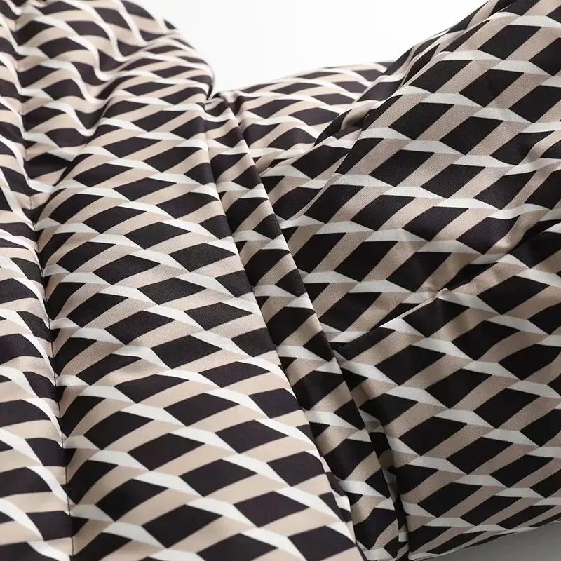 Close-up of padded jacket fabric with a geometric diamond print in black, white, and beige.
